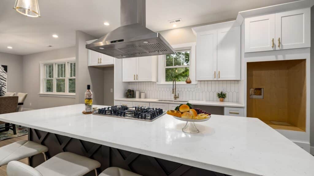 the brown cabinets in the island provide this kitchen a unique look and delivers contrast to the white cabinets and white quartz countertops